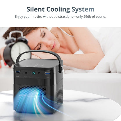 Photography of a black portable projector on a marble table featuring a blue glowing cooling vent and multiple ports, with a woman sleeping peacefully in a white bed and a black alarm clock visible in the background