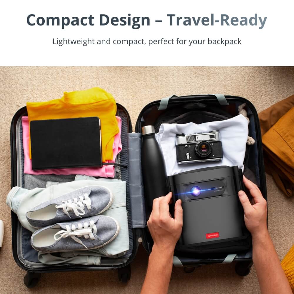 A pair of hands placing a compact black projector emitting blue light into a suitcase filled with travel items including a vintage silver camera, grey sneakers, and colorful clothing