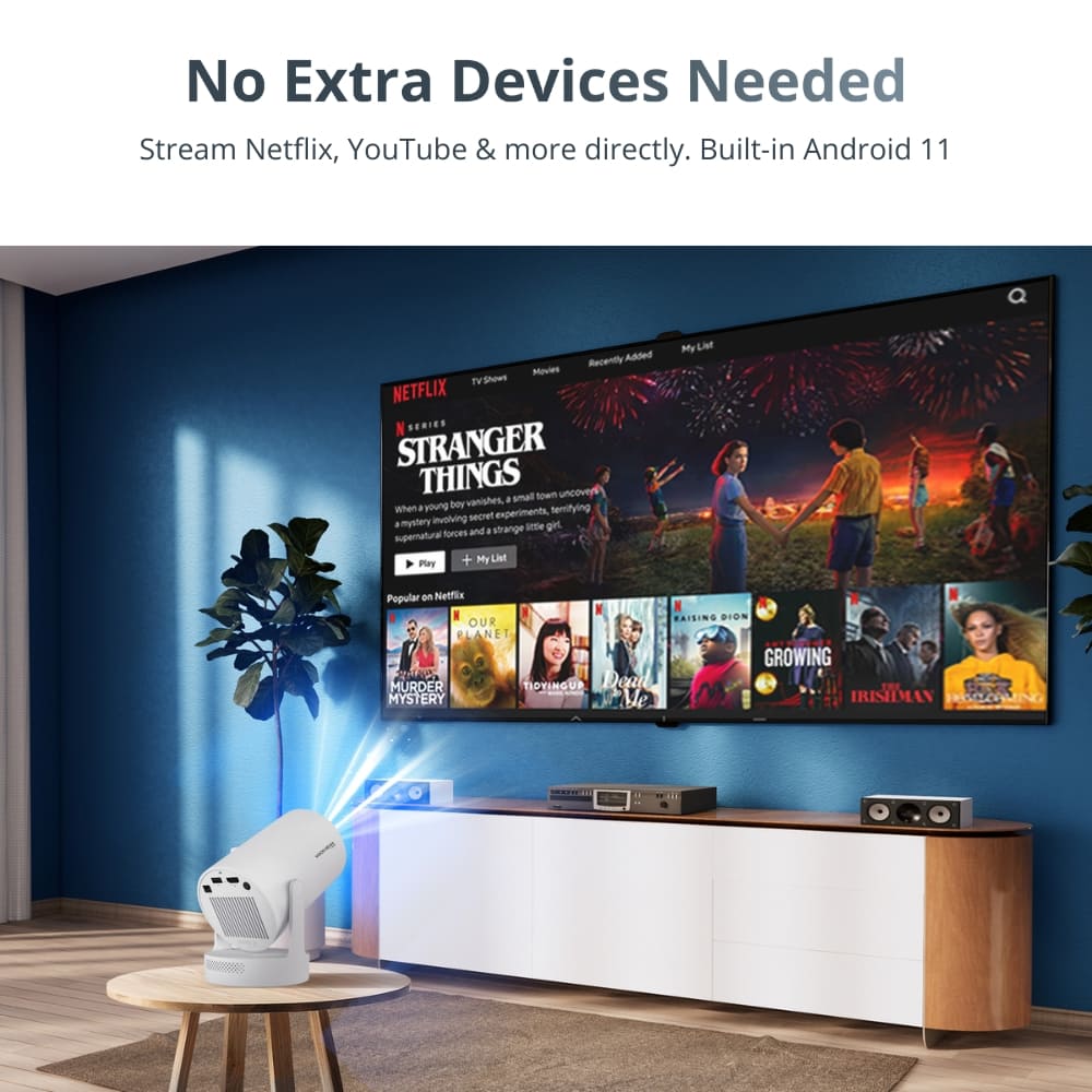 A white smart projector projecting Netflix's Stranger Things with colorful fireworks onto a large screen in a modern living room with a dark blue accent wall